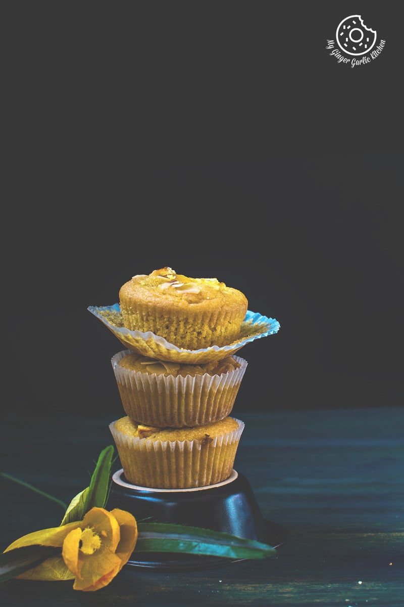 three eggless orange olive oil muffins stacked on top of each other on a table