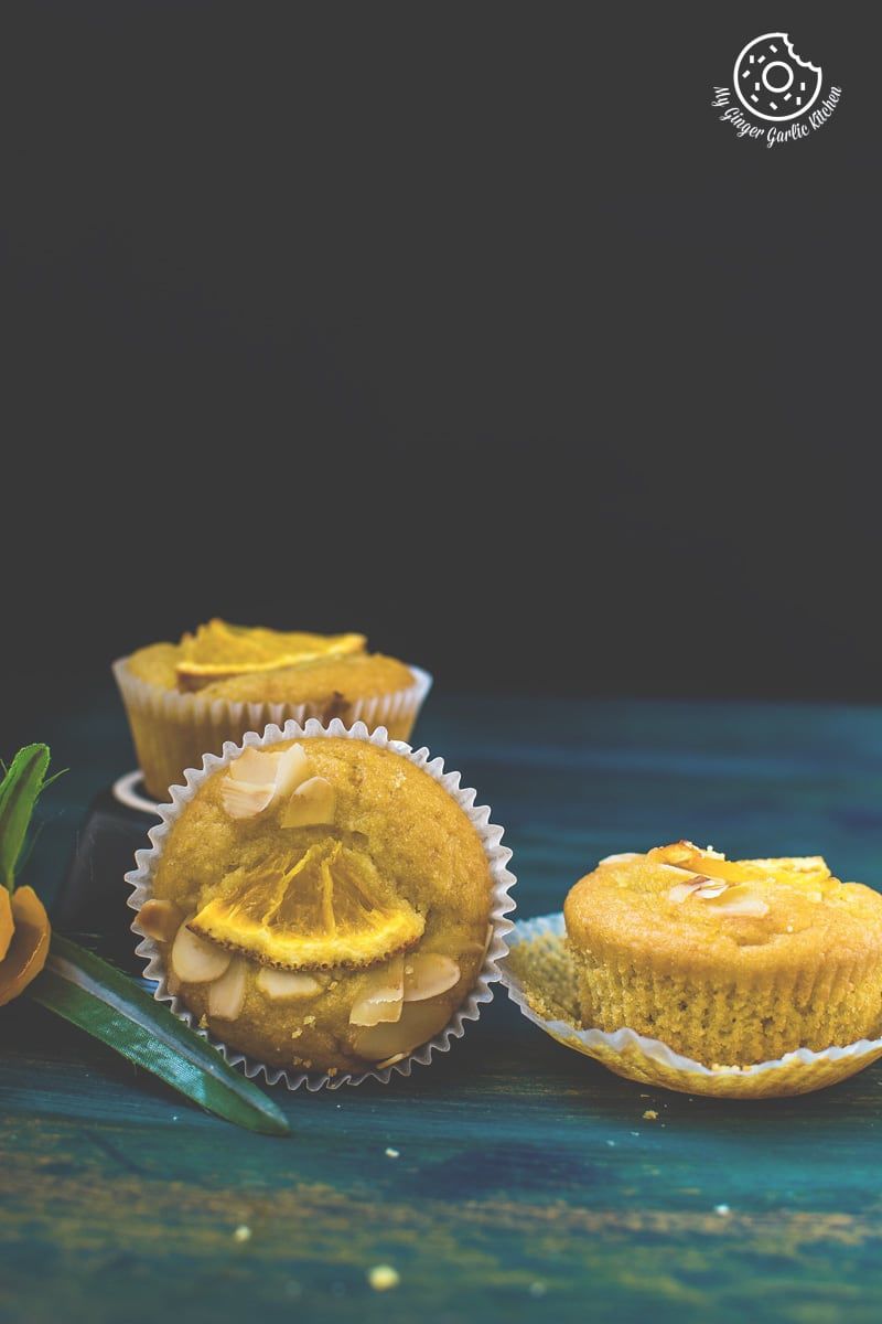 three eggless orange olive oil muffins sitting on a table