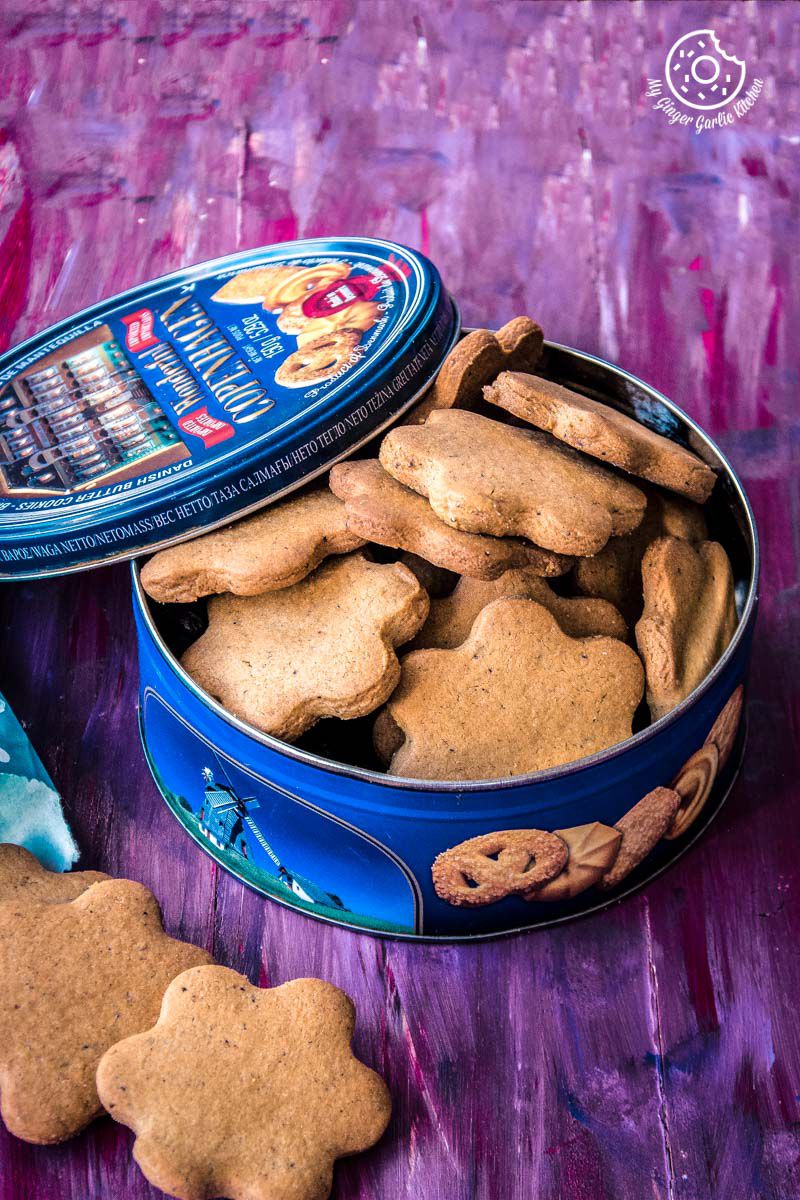 some indian atta biscuits or cookies in a tin and a bag of chips