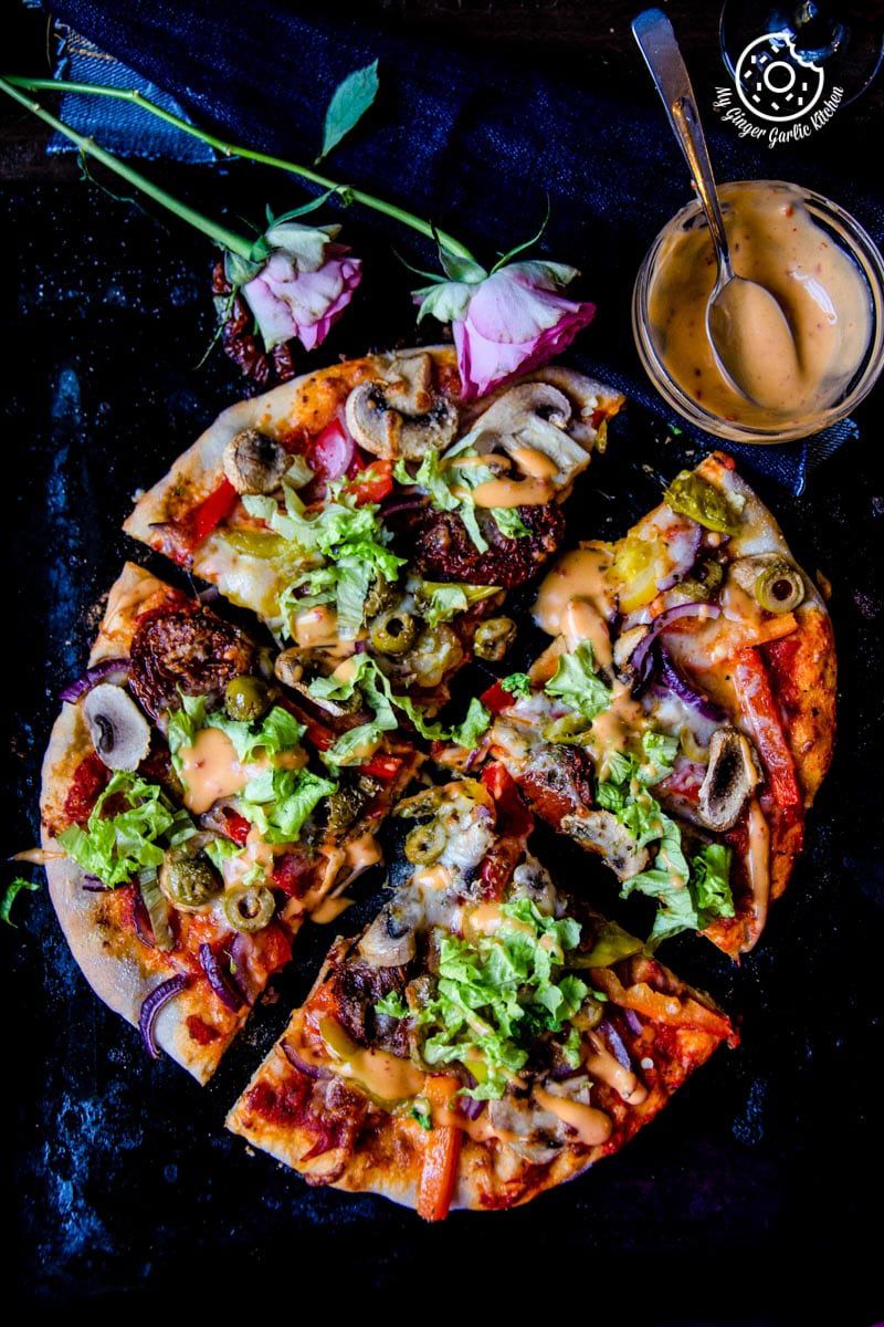 a vegetarian pizza with several toppings on a black plate