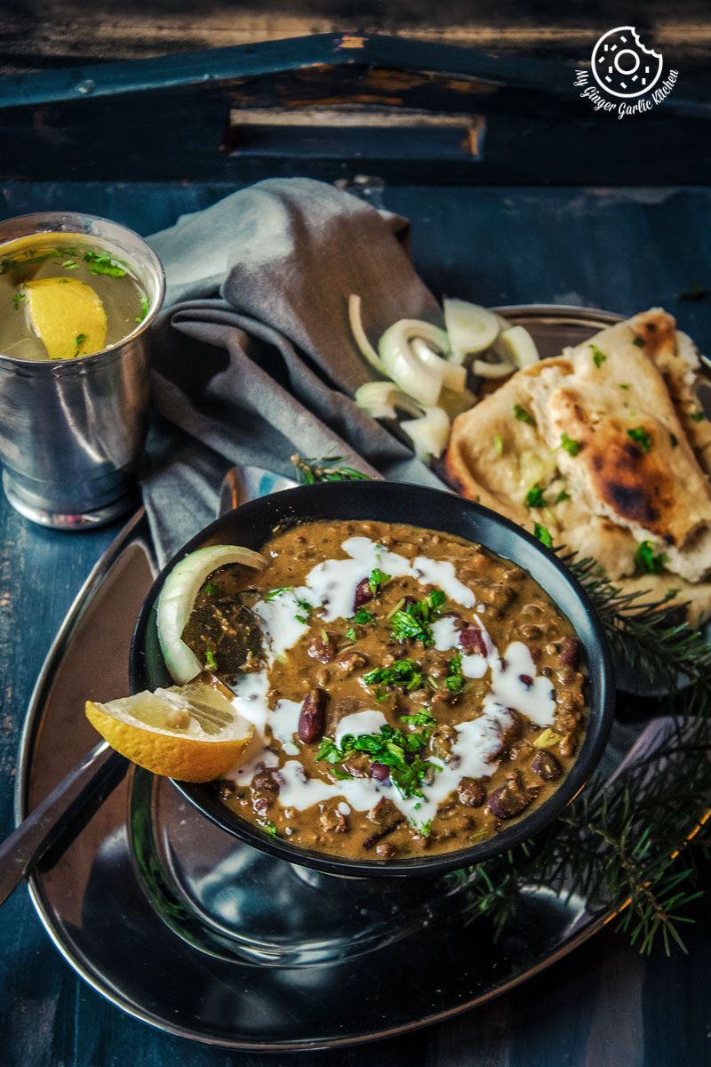 there is a bowl of Restaurant Style Dal Makhani and naan on a plate on a table