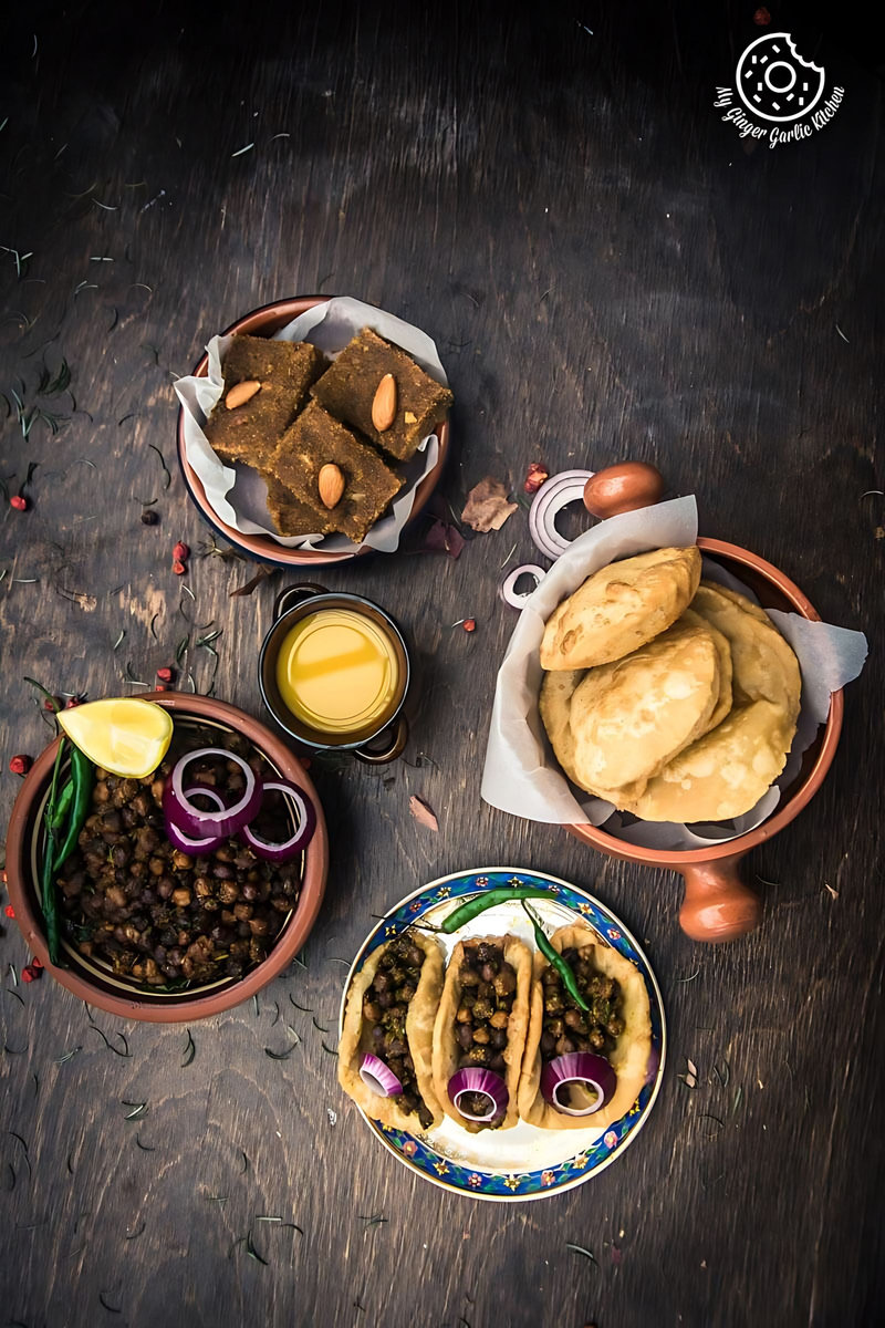 several plates of halwa chana poori ashtami prashad are arranged on a table with a bowl of bread