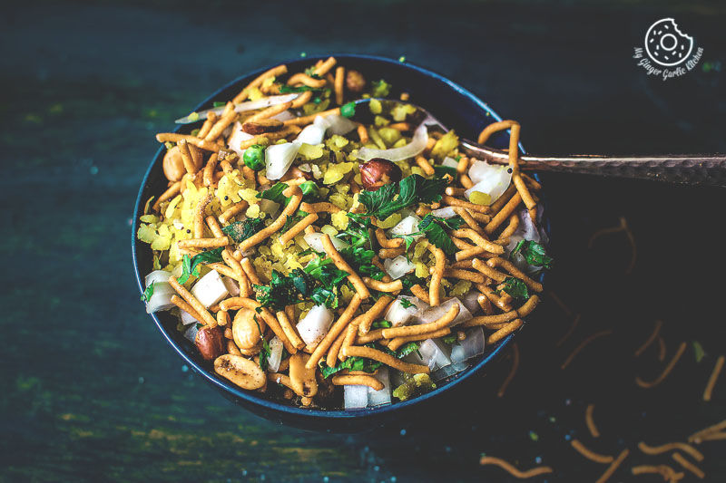 a bowl of khatta meetha indori poha with a topping of sev and cilantro 