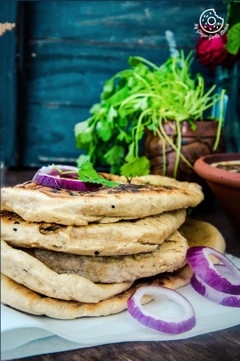 a stack of paneer stuffed naan with onions and herbs