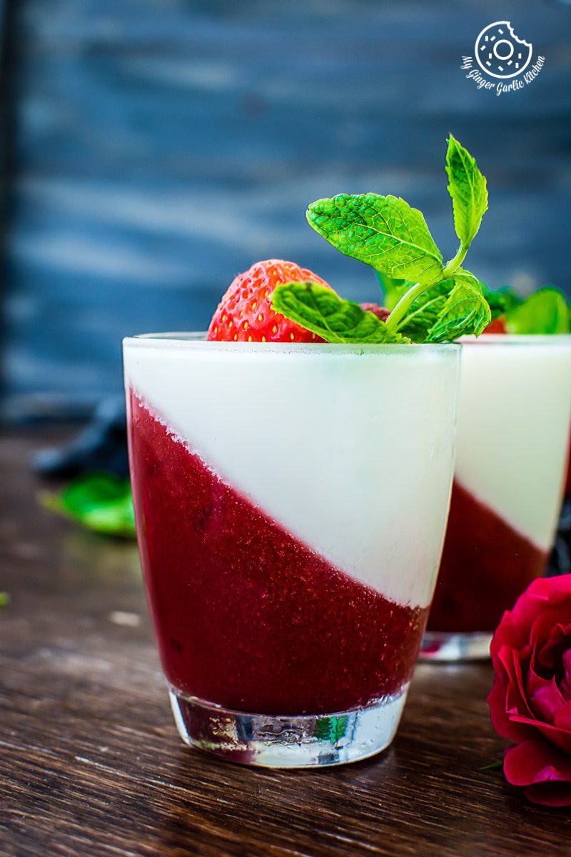 two glasses of strawberry panna cotta with strawberries and a rose