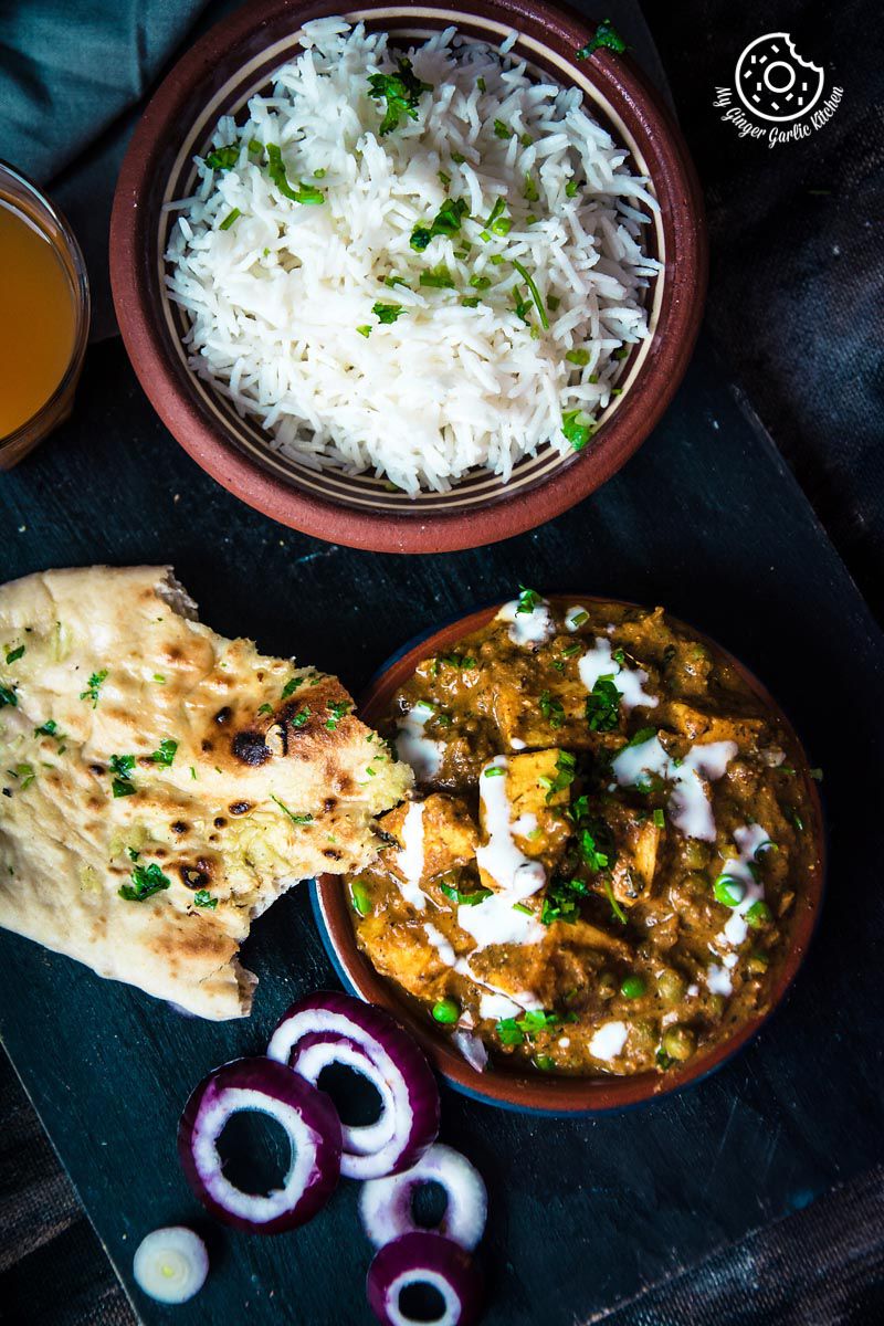 there is a plate of matar paneer curry with rice, naan and a bowl of steamed rice