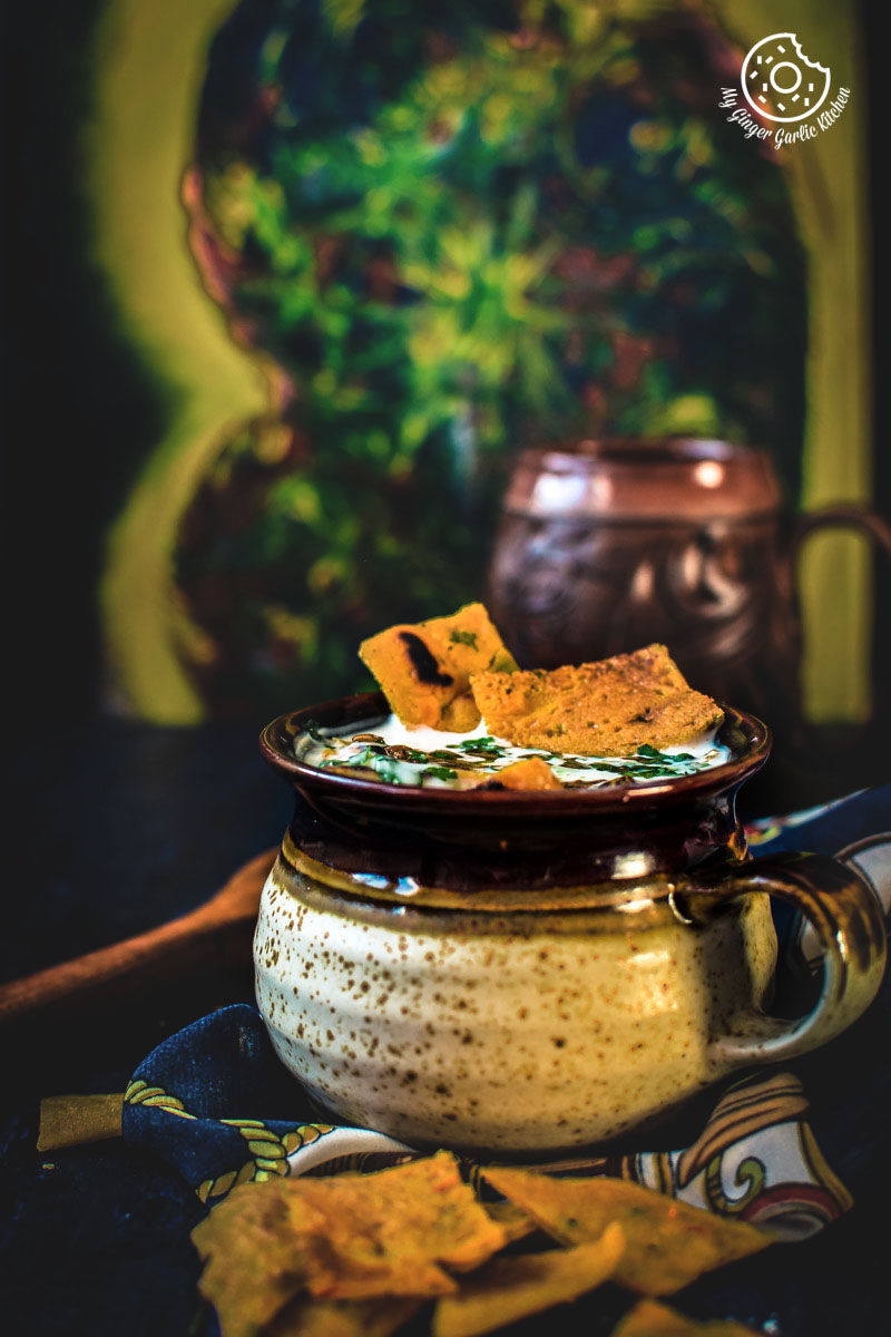 a bowl of rajasthani besan ke cheele ka raita with chilla on the side on a table
