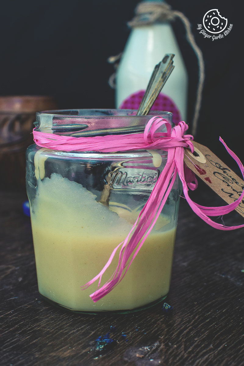 a jar of homemade sweetened condensed milk with a pink ribbon on it