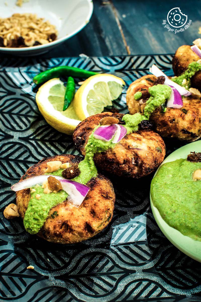 some dahi ke kababs on a plate with a bowl of green chutney