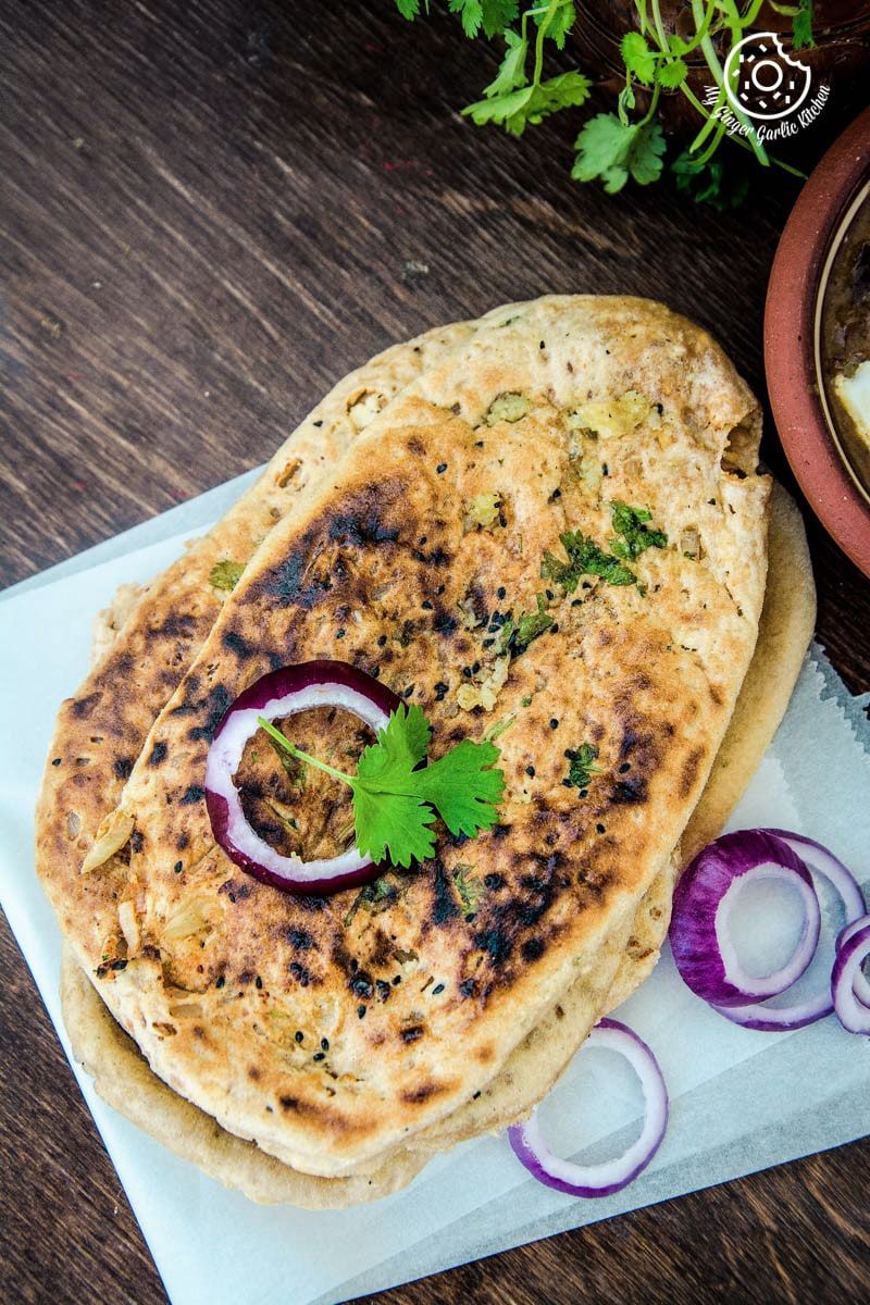 a stack of paneer stuffed naan with onions and herbs