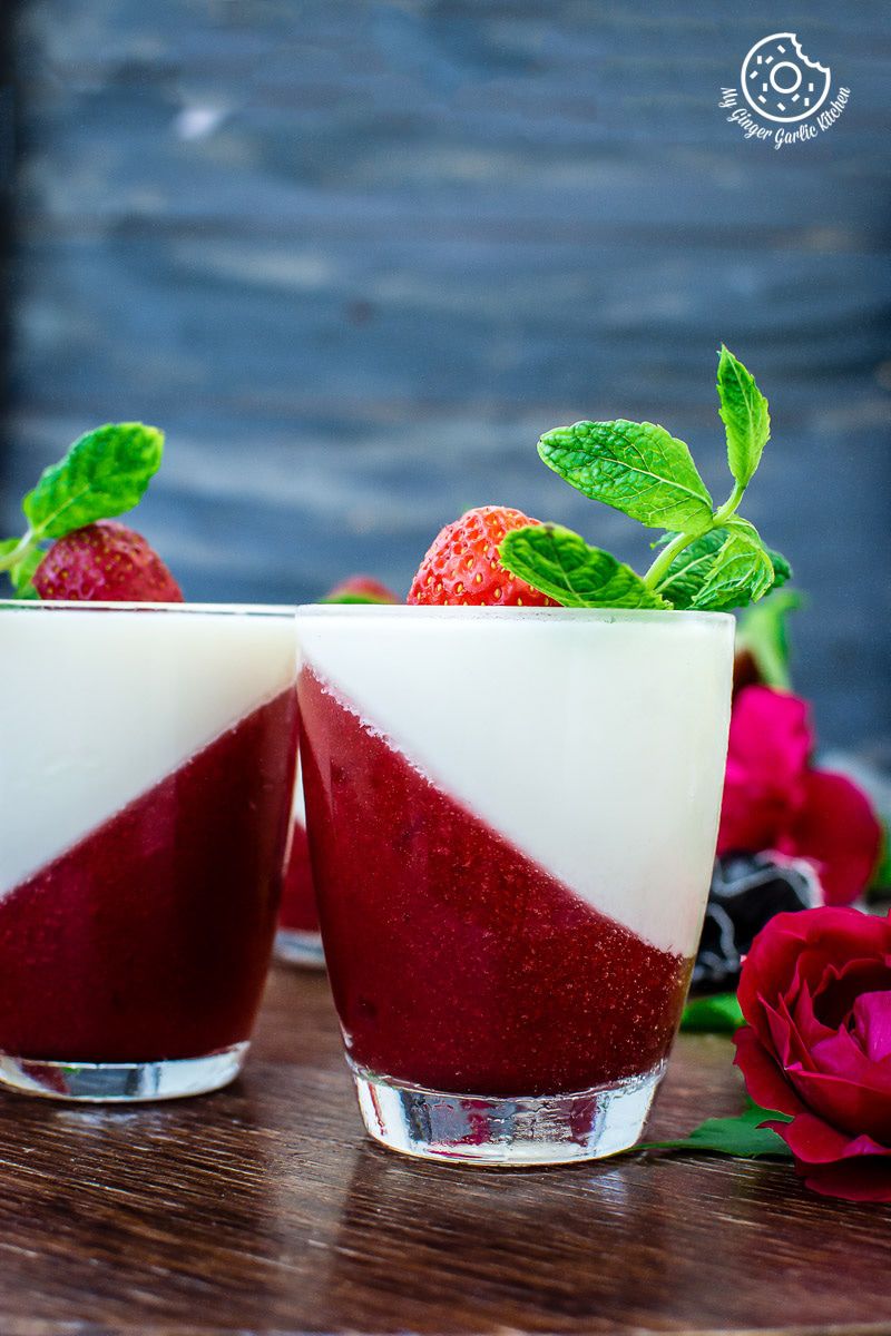 two cups of strawberry panna cotta with strawberries and mint leaves