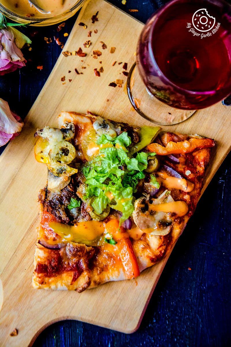 a vegetarian Italian pizza on a cutting board with a glass of wine