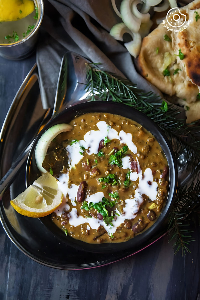 there is a bowl of Restaurant Style Dal Makhani with a spoon and a lemon wedge