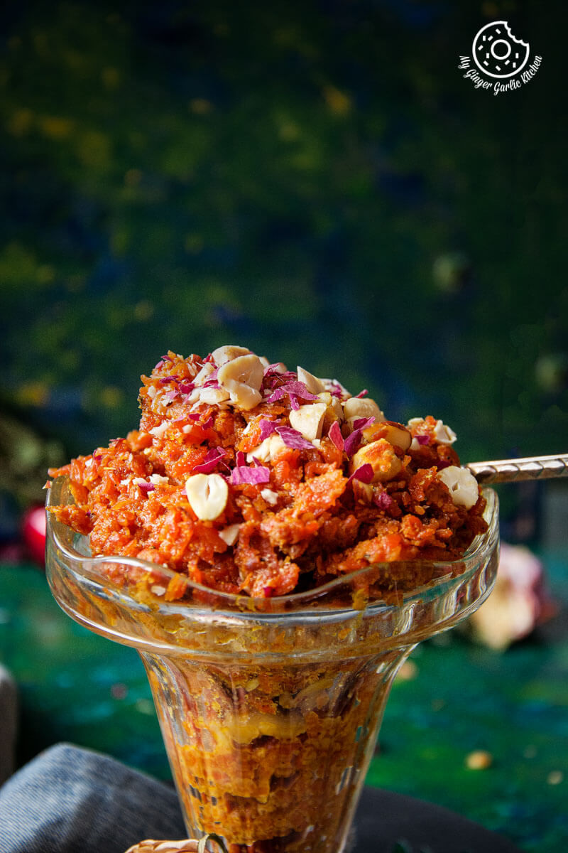 a glass bowl filled with gajar ka halwa or carrot halwa and a spoon
