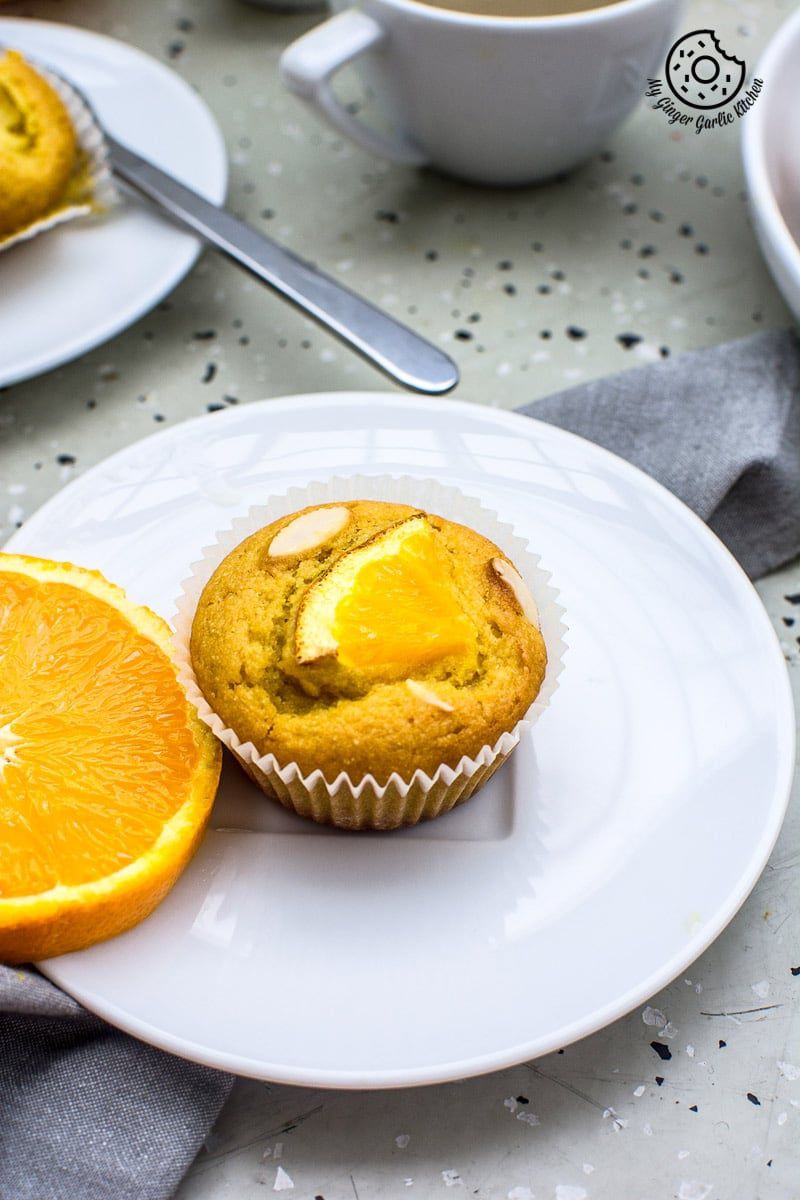a eggless orange olive oil muffin on a plate with a slice of orange