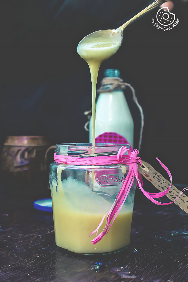 a spoon with sweetened condensed milk pouring into a jar