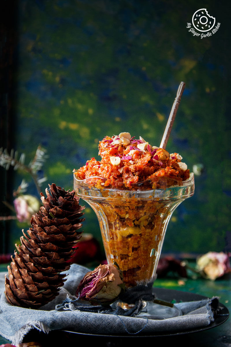 a bowl of gajar ka halwa with a spoon and a pine cone