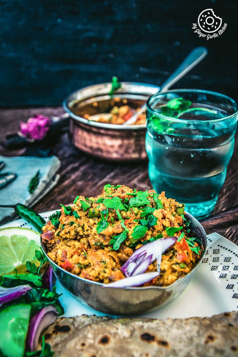 a bowl of punjabi paneer bhurji dry on a plate with a glass of water