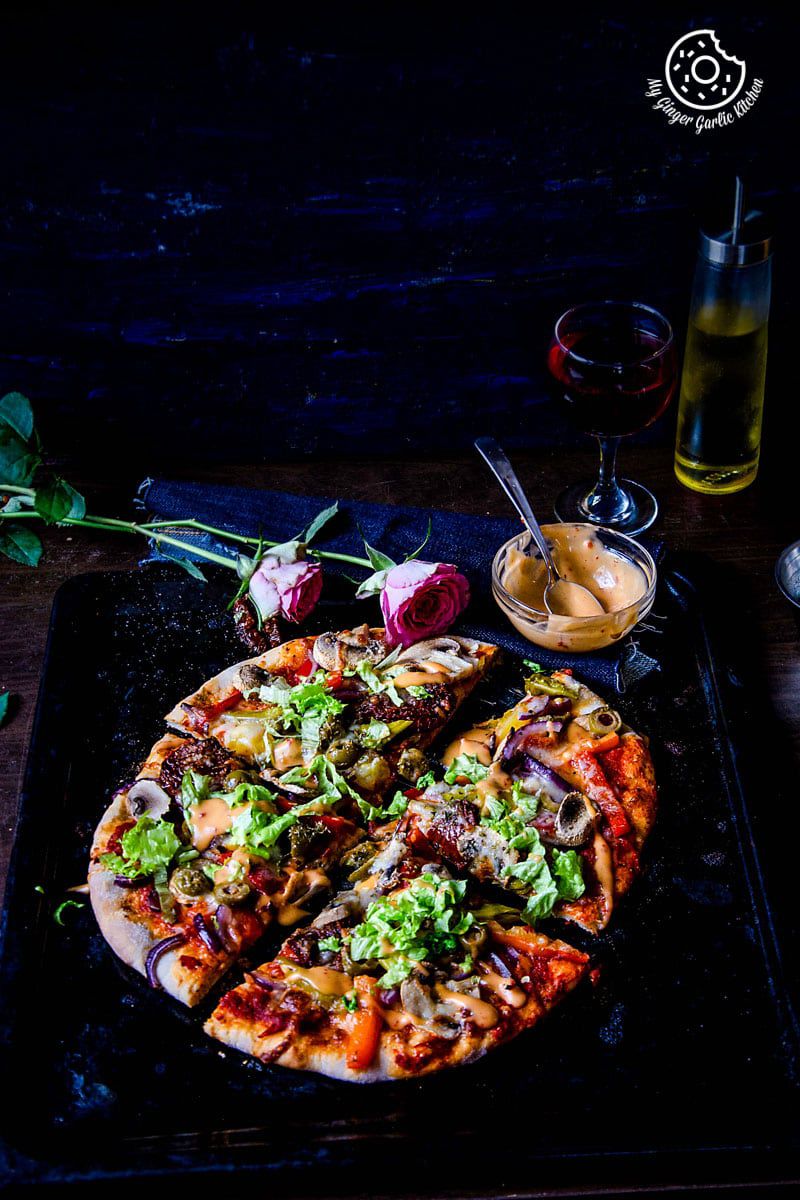 a vegetarian pizza with vegetables and sauce on a black plate