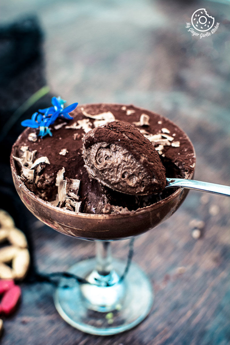 vegan aquafaba chocolate mousse in a glass with a spoon and a blue flower