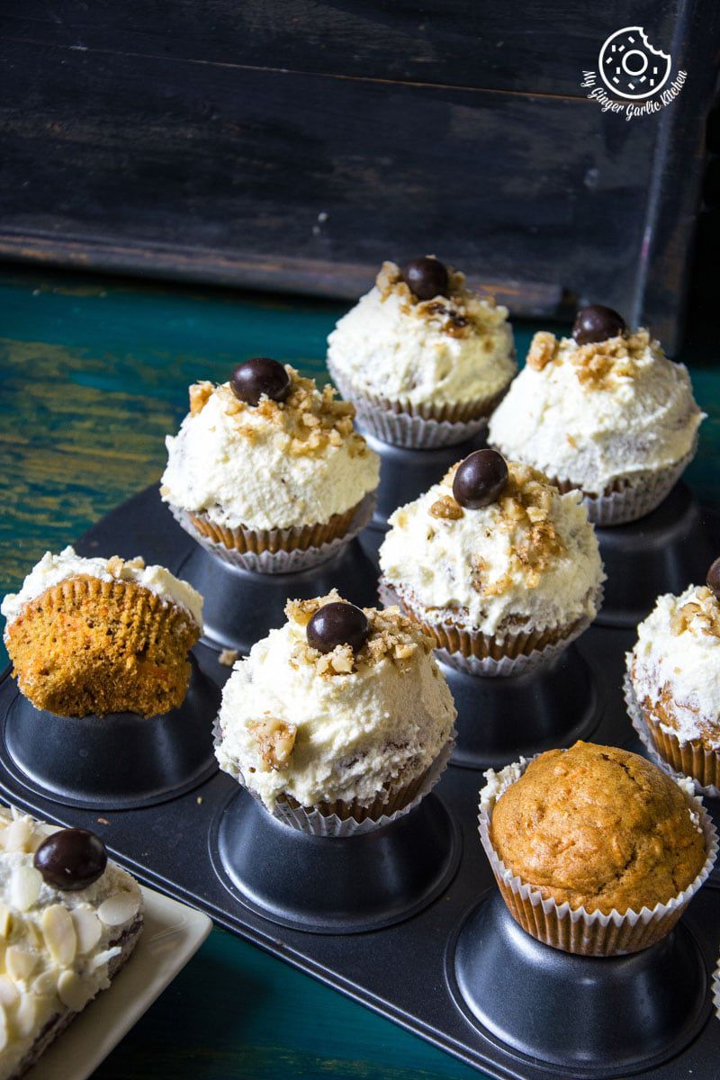 there are many carrot cake cupcakes with lemon ricotta frosting in a muffin tin on a table