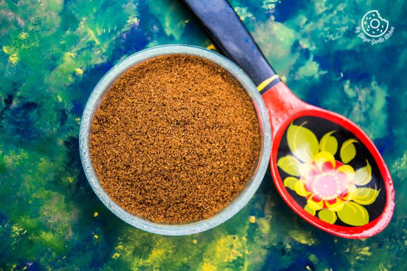 there is a bowl of roasted cumin powder next to a spoon on a table
