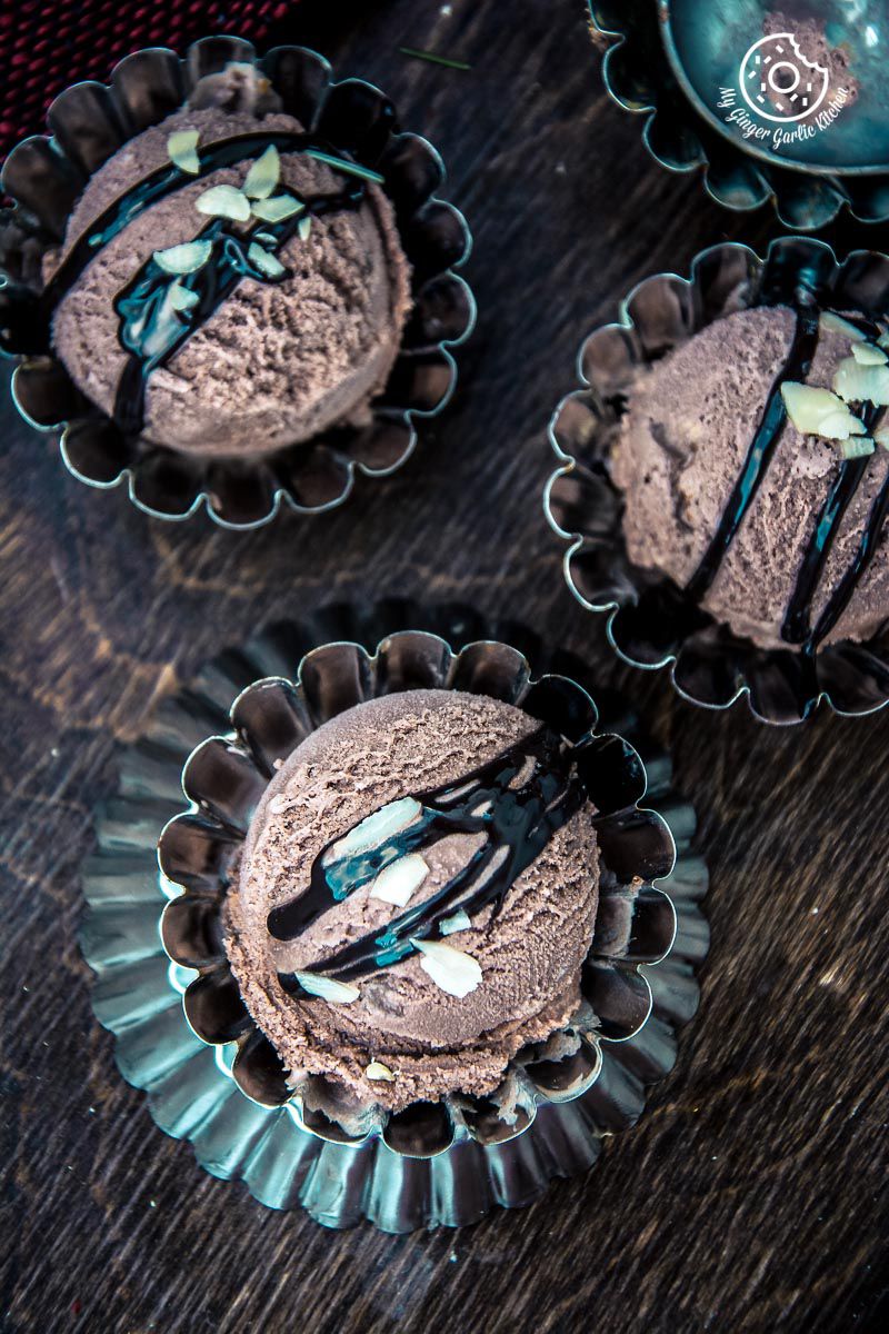 three eggless chocolate hazelnut ice creams with chocolate sauce and almond flakes
