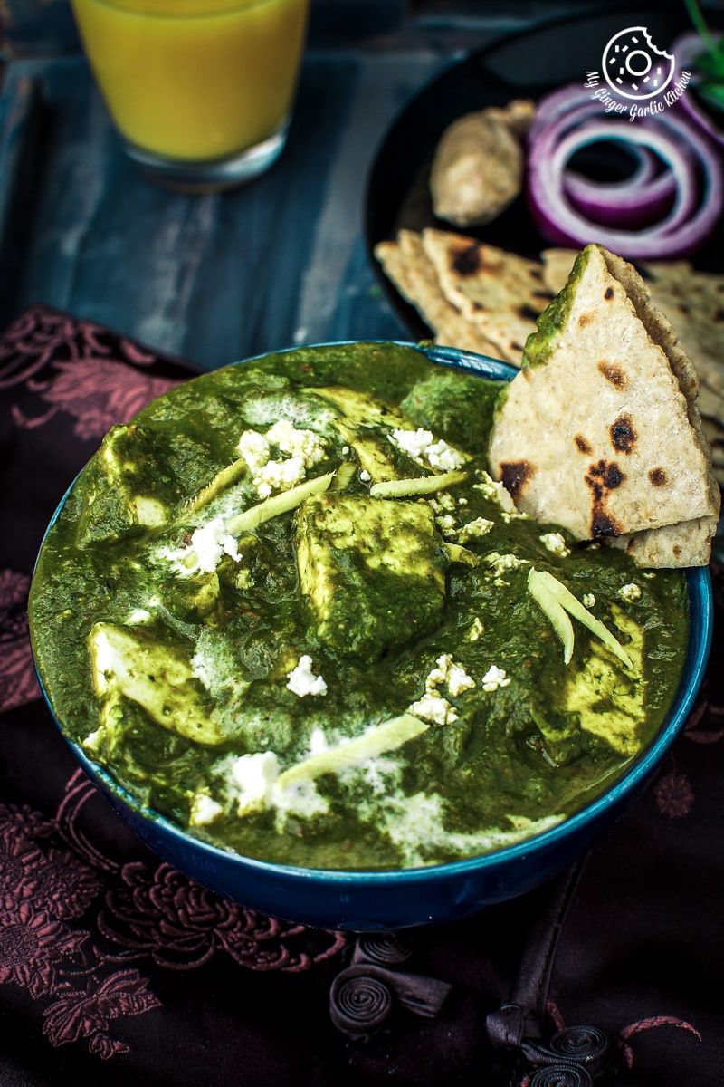 a bowl of palak paneer with some flatbreads