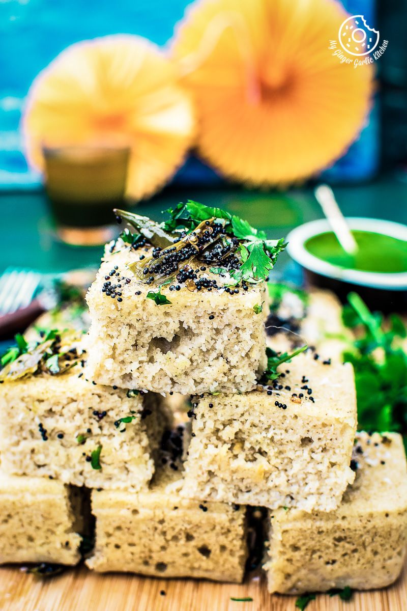 a stack of instant oats rava dhokla with a bunch of herbs on it
