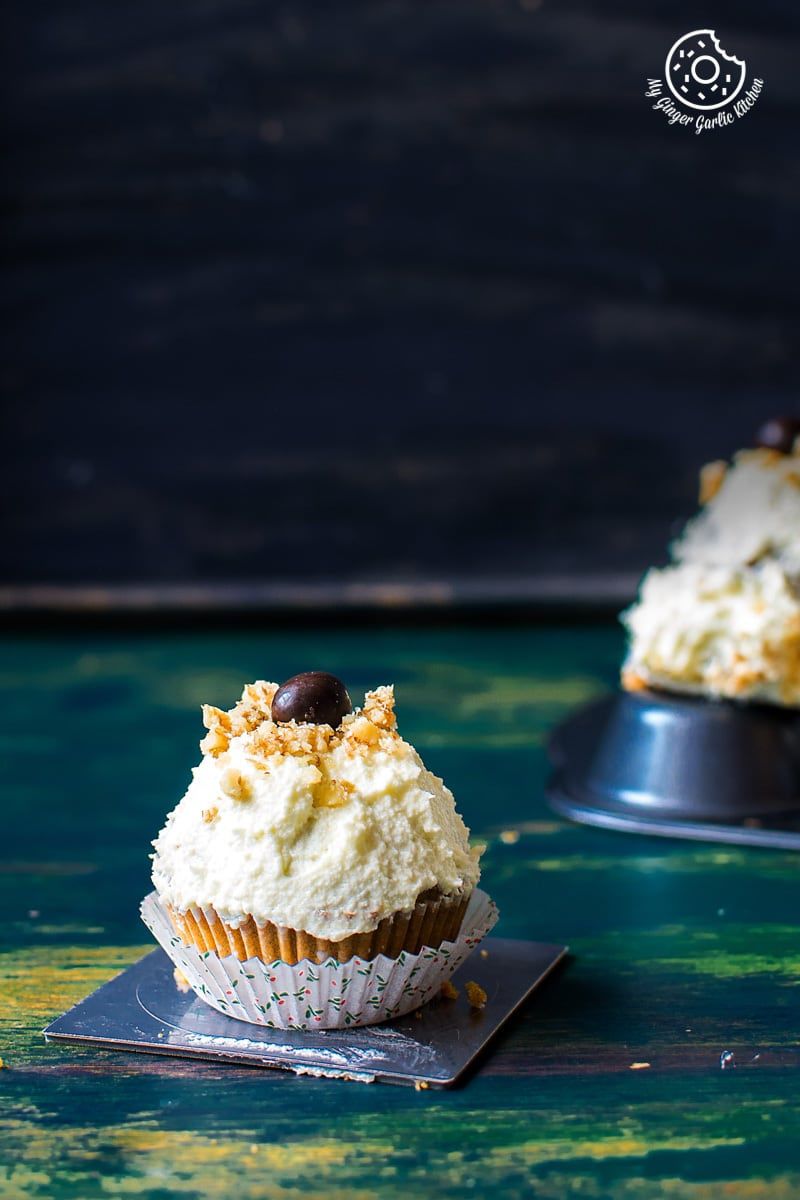 there are two carrot cake cupcakes with lemon ricotta frosting with white frosting and chocolate toppings
