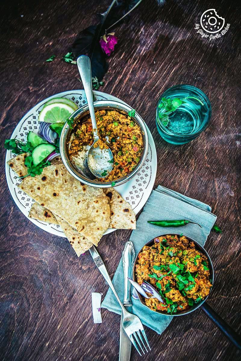 a plate of food with a spoon and a bowl of punjabi paneer bhurji dry