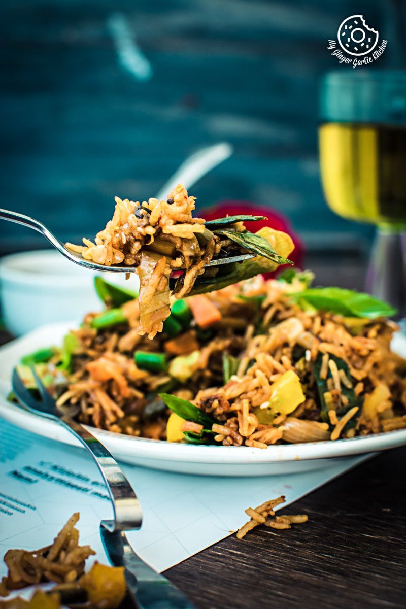 a plate of veg schezwan fried rice with a fork full of food