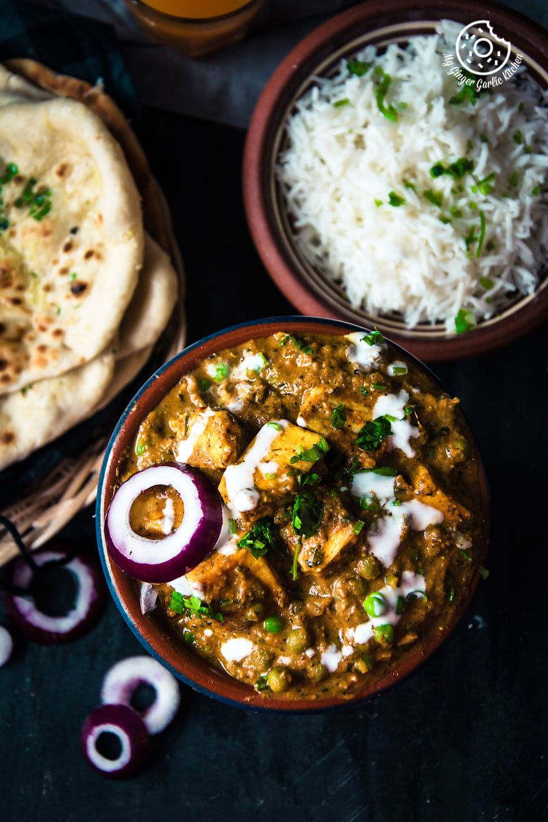 there is a bowl of matar paneer curry with rice and a bowl of bread