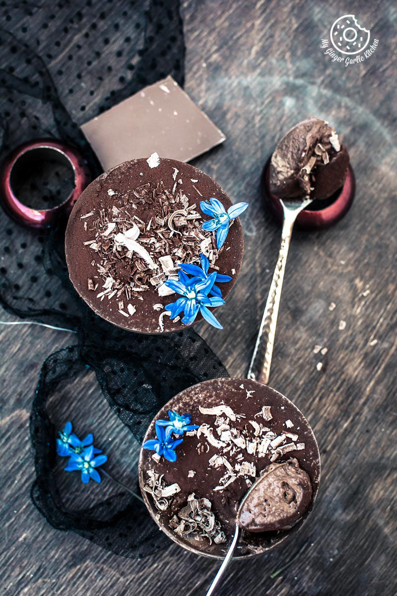 two vegan aquafaba chocolate mousse glasses on a table with a spoon