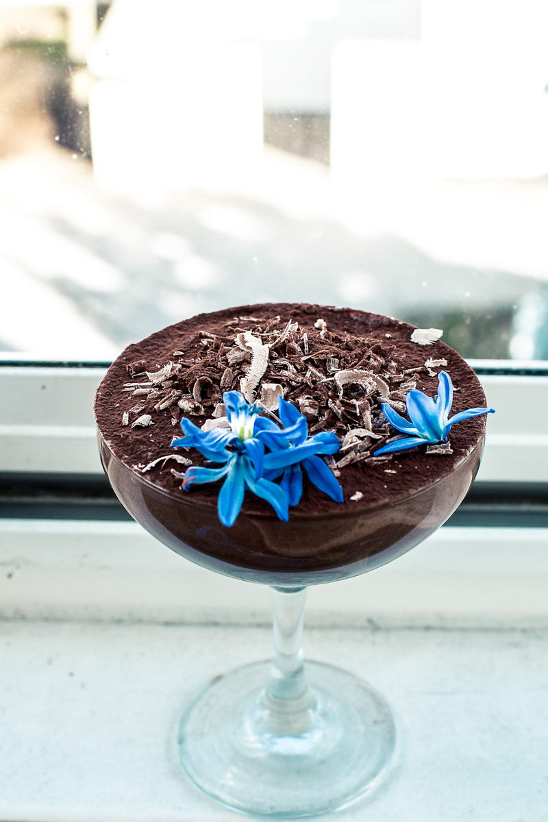 a vegan aquafaba chocolate mousse with blue flowers on top of it