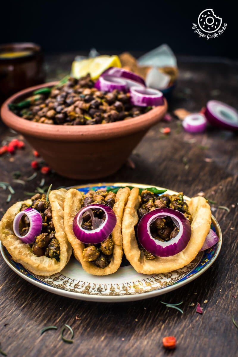 there are three puris on a plate with kala chana and onions