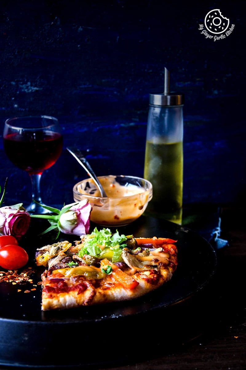 a vegetarian pizza on a plate with a glass of wine