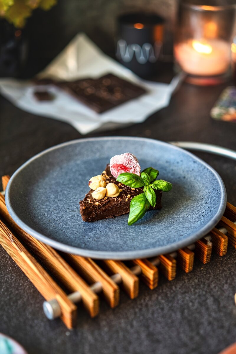 Single slice of no bake chocolate banana cake with hazelnuts raspberry and basil garnish