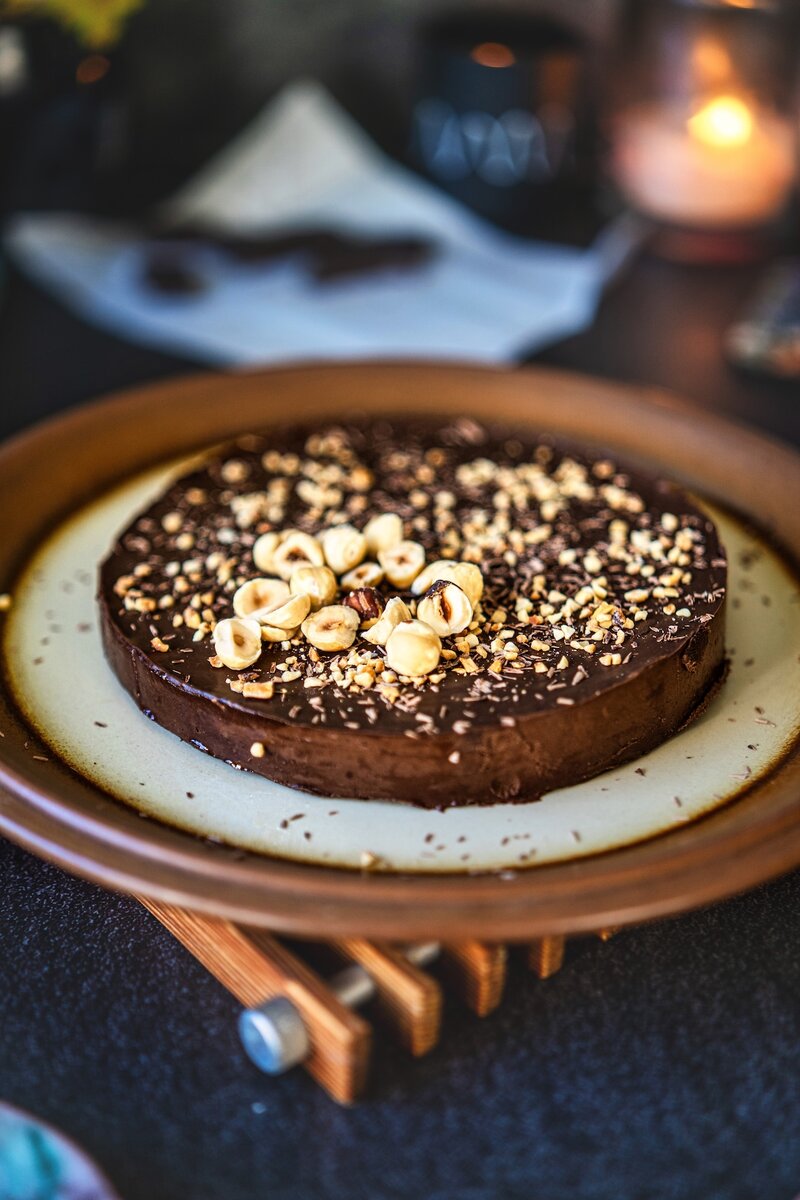 Healthy no bake chocolate banana cake on ceramic plate with chopped hazelnuts