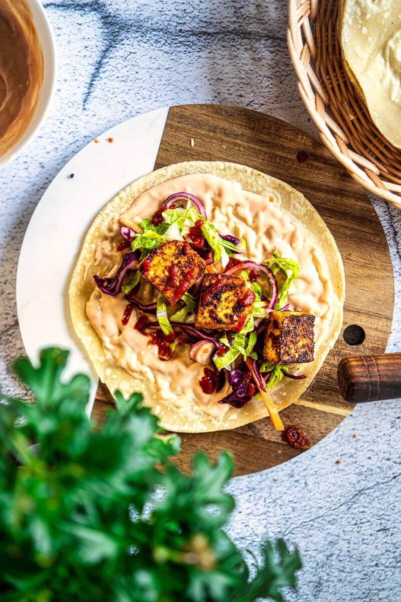 high protein cottage cheese tortilla wrap with tofu filling, vegetables, and creamy sauce on flatbread