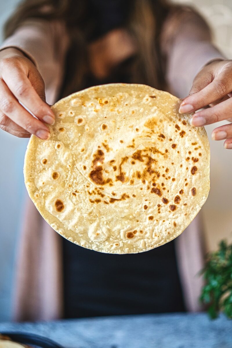 soft and flexible 2 ingredient cottage cheese tortilla held by hands showing texture and light browning