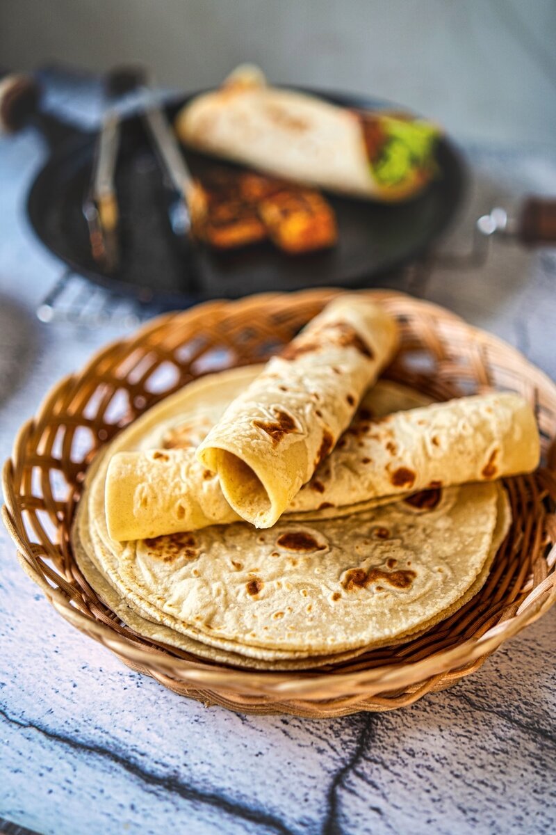 stack of homemade cottage cheese tortillas with rolled wraps showing soft and flexible texture