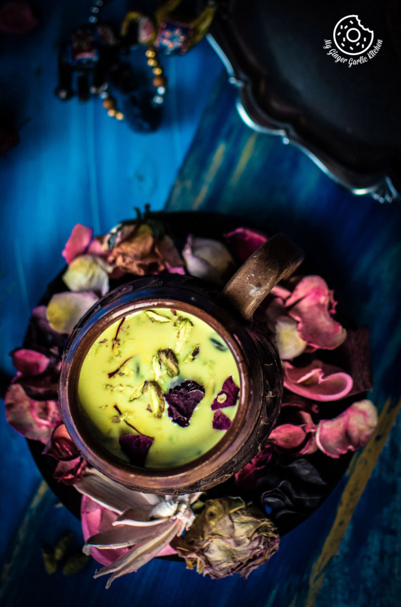 a glass of thandai with dried flowers on a plate