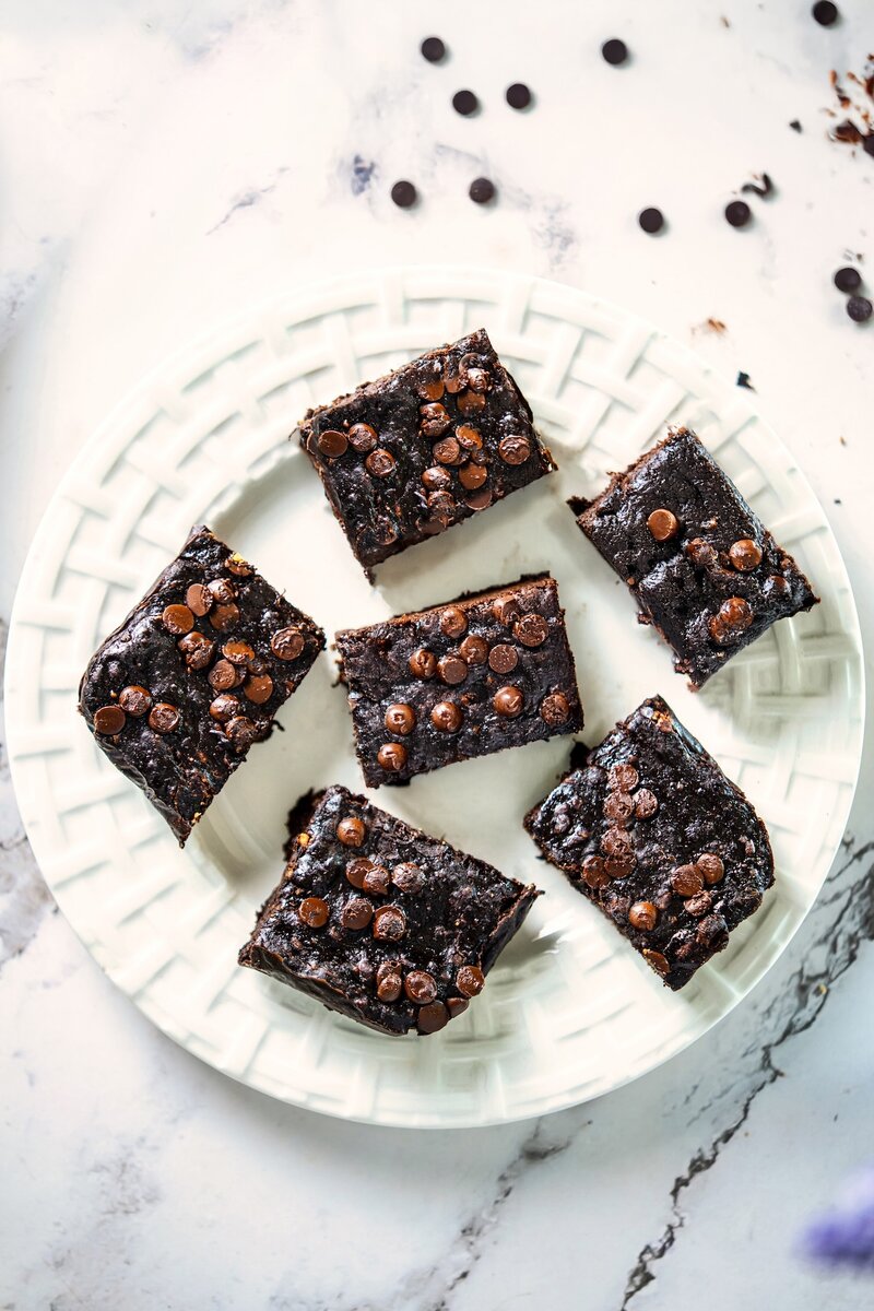 Top view of 3-ingredient banana peanut butter brownies topped with dairy-free chocolate chips on a white plate