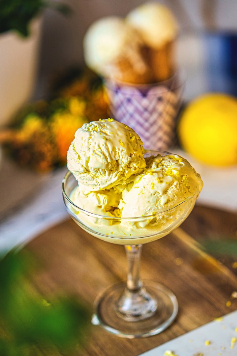 Creamy homemade 3 ingredient lemon ice cream served in a glass dessert bowl with fresh lemon zest on top.