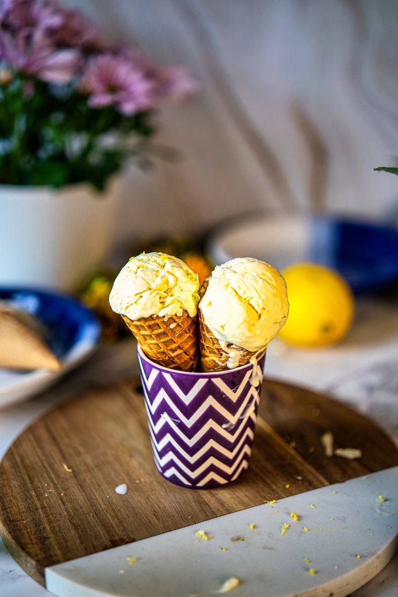 Two waffle cones filled with homemade 3 ingredient lemon ice cream in a decorative cup.