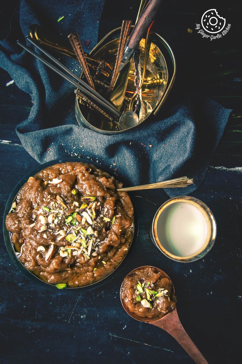 a plate of atta halwa with a spoon and a glass of milk