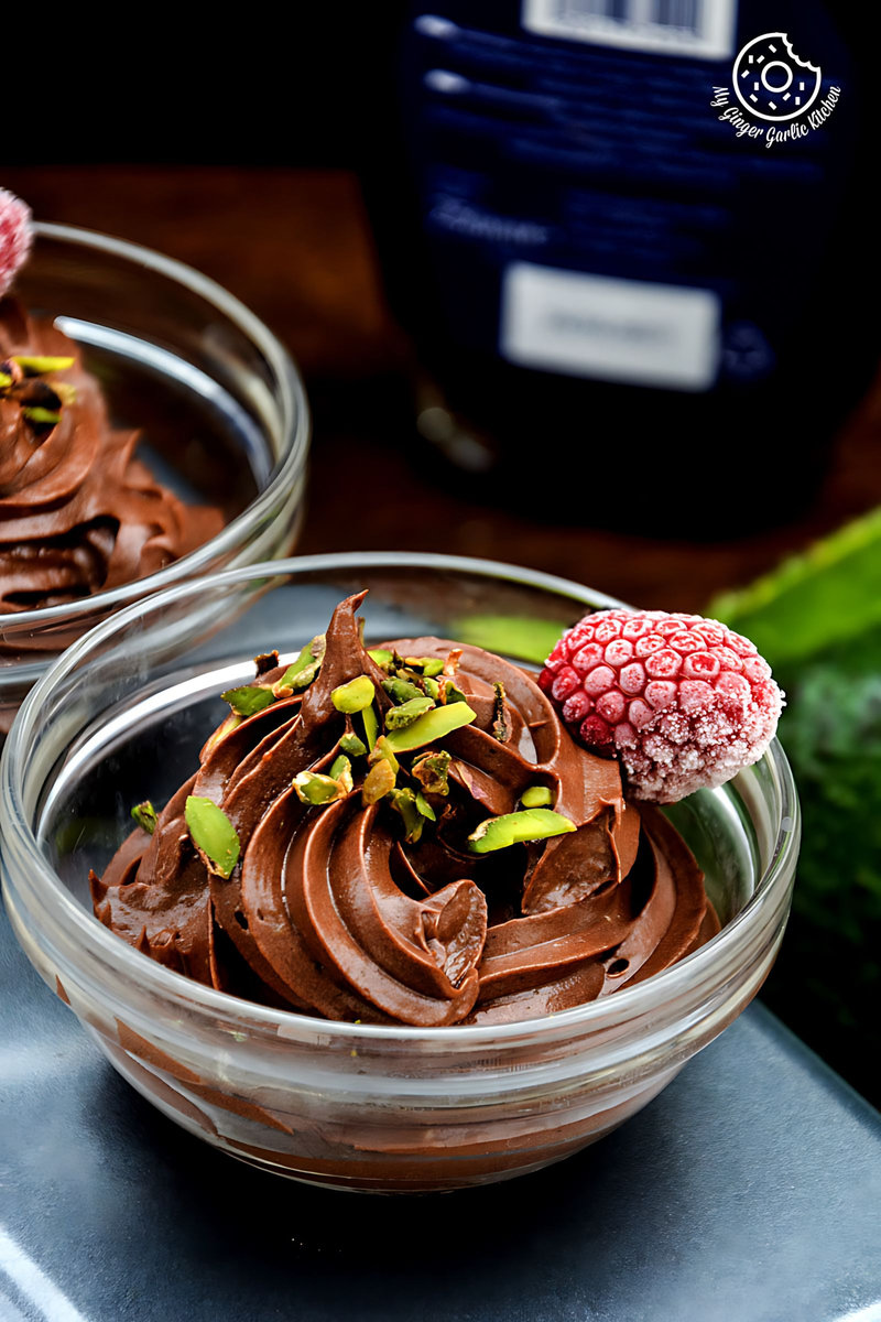 two bowls of avocado chocolate mousse with raspberries on top