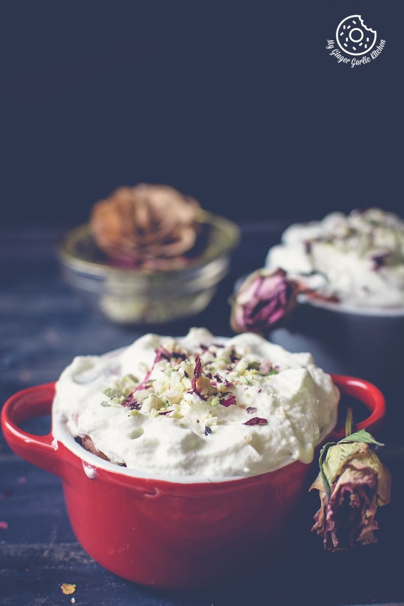a red mini casserole dish with eggless gulknad mug cake with whipped cream and flowers