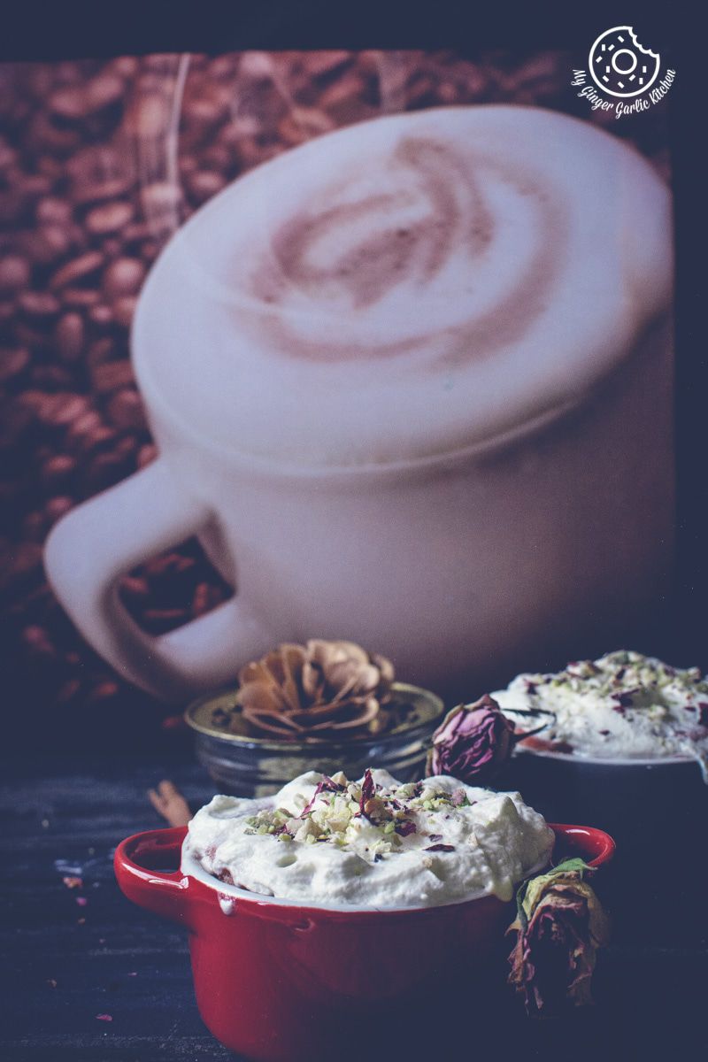 two red mini casserole dishes filled with eggless gulknad mug cake with whipped cream and flowers